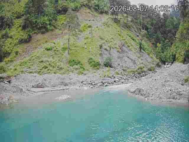 Daytime monitoring frame of a turquoise river beside a debris-flow slope